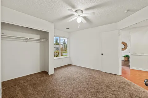 an empty room with ceiling fan and window