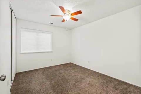 an empty room with ceiling fan and windows