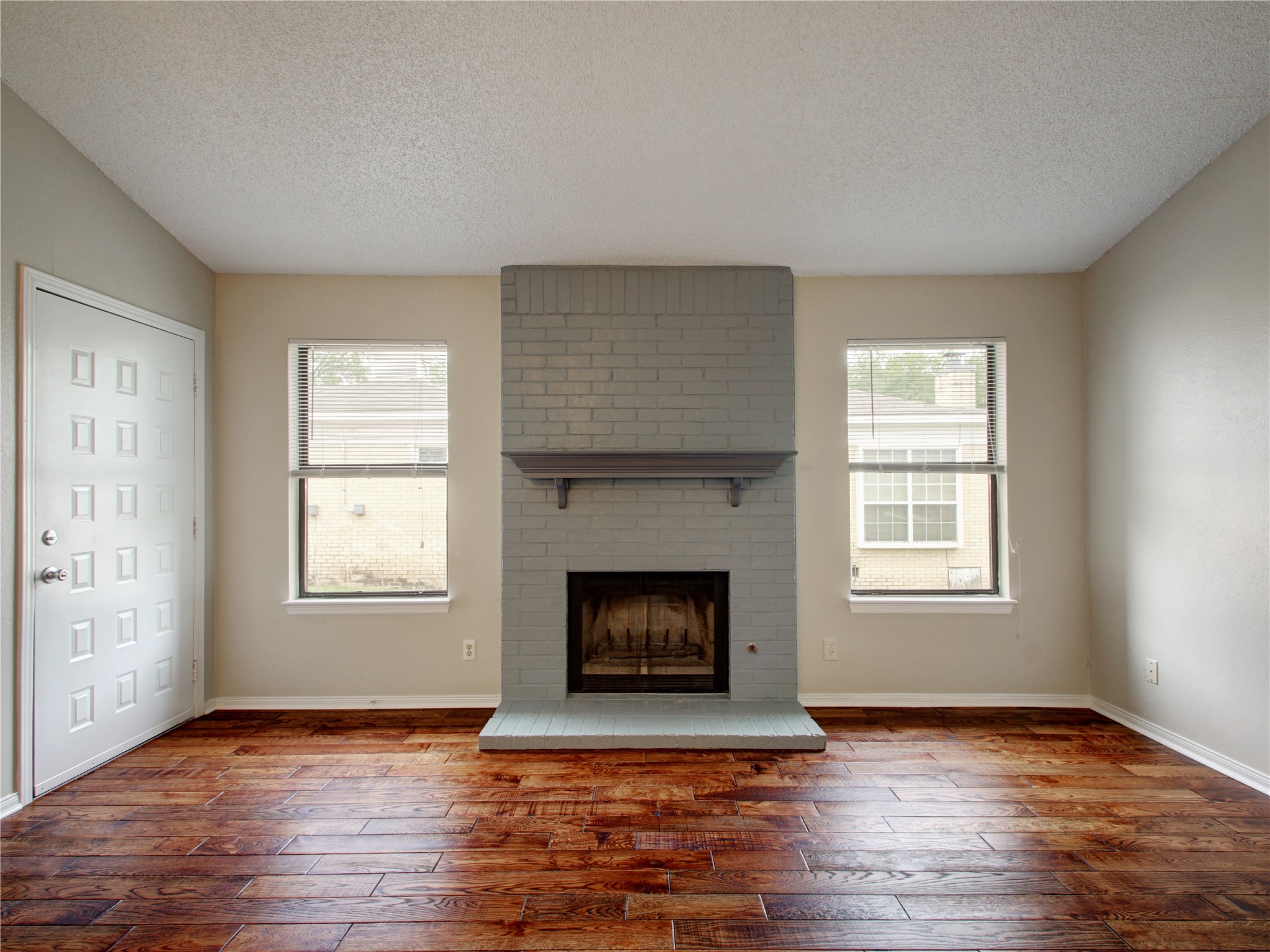 4703 Rosedale Avenue, Unit A Austin, TX 78756 - Photo 5 of 19 Unfurnished living room with a textured ceiling, a brick fireplace, dark wood finished floors, and plenty of natural light