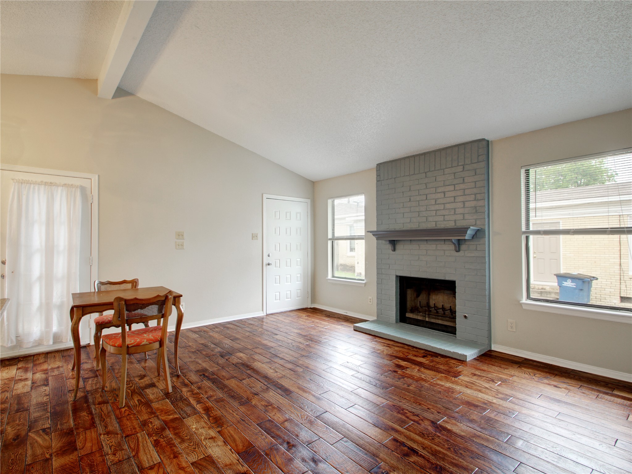 4703 Rosedale Avenue, Unit A Austin, TX 78756 - Photo 6 of 19 Living room featuring a brick fireplace, a textured ceiling, dark wood finished floors, and healthy amount of natural light