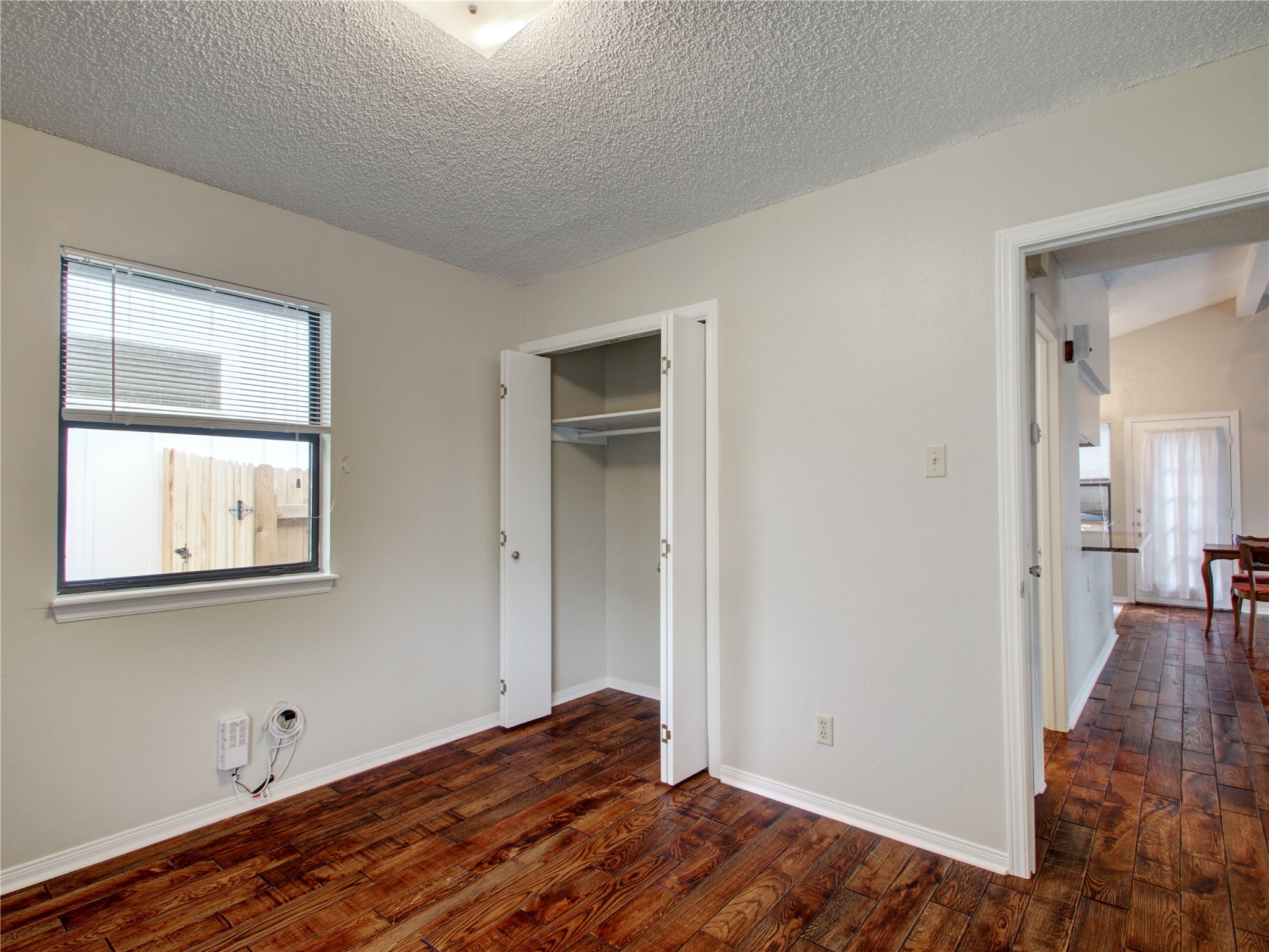 4703 Rosedale Avenue, Unit A Austin, TX 78756 - Photo 10 of 19 Unfurnished bedroom featuring dark wood-style flooring, a textured ceiling, and a closet