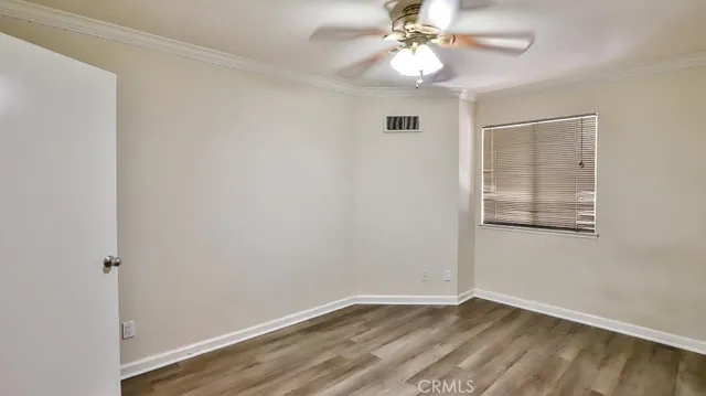 an empty room with wooden floor chandelier fan and windows