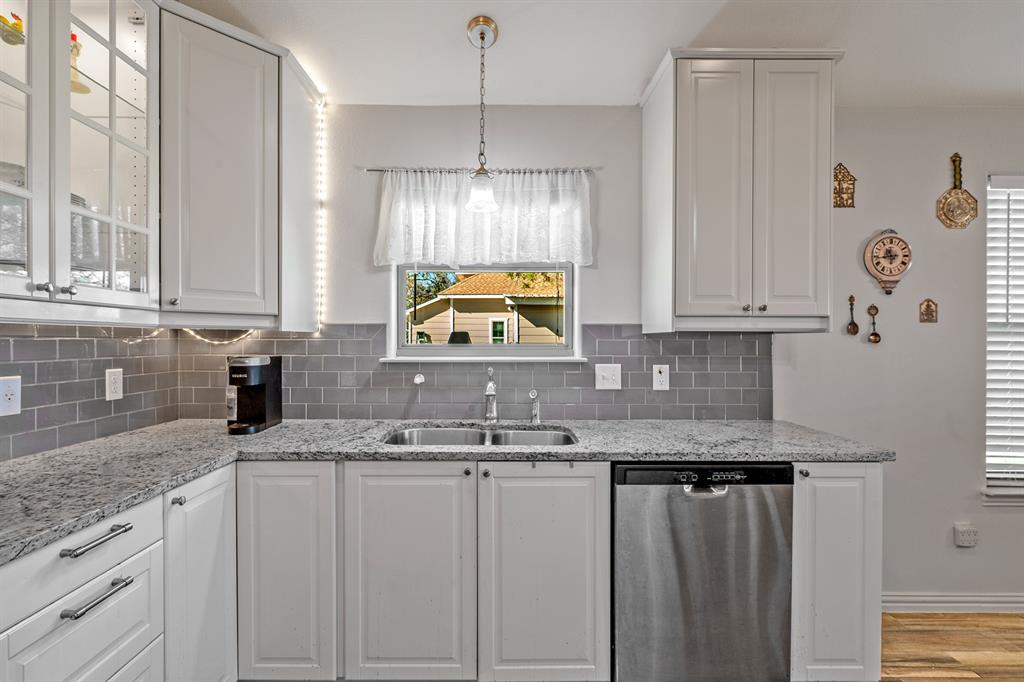 1209 Sherman Street Tioga, TX 76271 - Photo 21 of 40 a kitchen with granite countertop a sink a window and cabinets