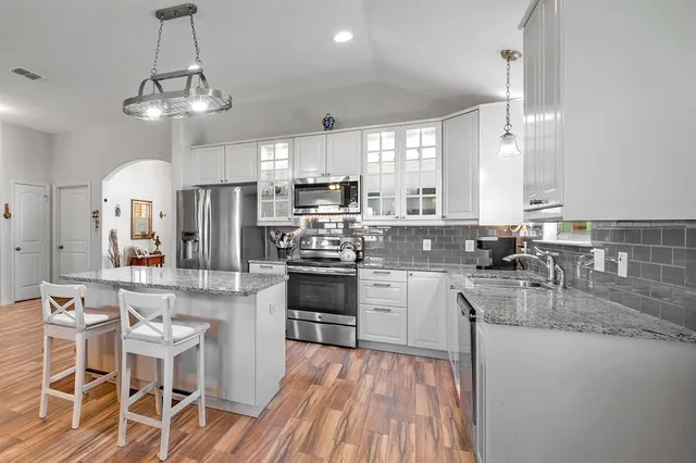 a kitchen with stainless steel appliances a dining table chairs stove refrigerator and cabinets