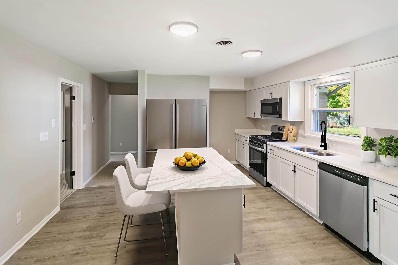 1431 West Vanmeter Street Kankakee, IL 60901 - Photo 5 of 19 a kitchen with stainless steel appliances a dining table chairs refrigerator and microwave