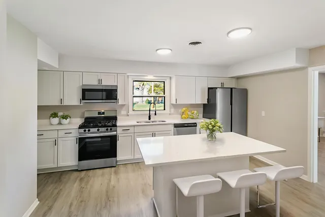 a kitchen with stainless steel appliances a dining table chairs stove refrigerator and microwave