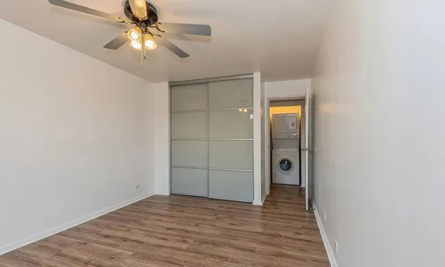 a view of empty room with wooden floor and fan