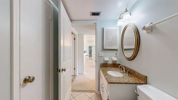 a bathroom with a granite countertop toilet a sink and a mirror