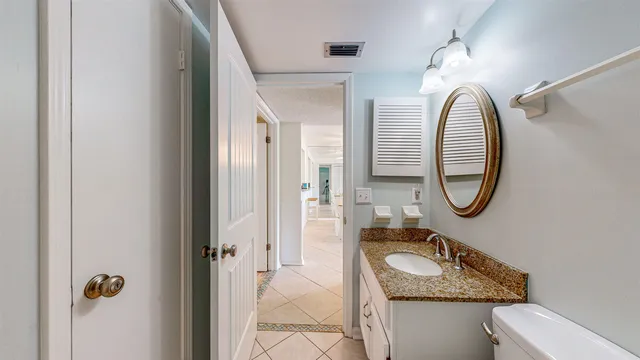 a bathroom with a granite countertop toilet a sink and a mirror