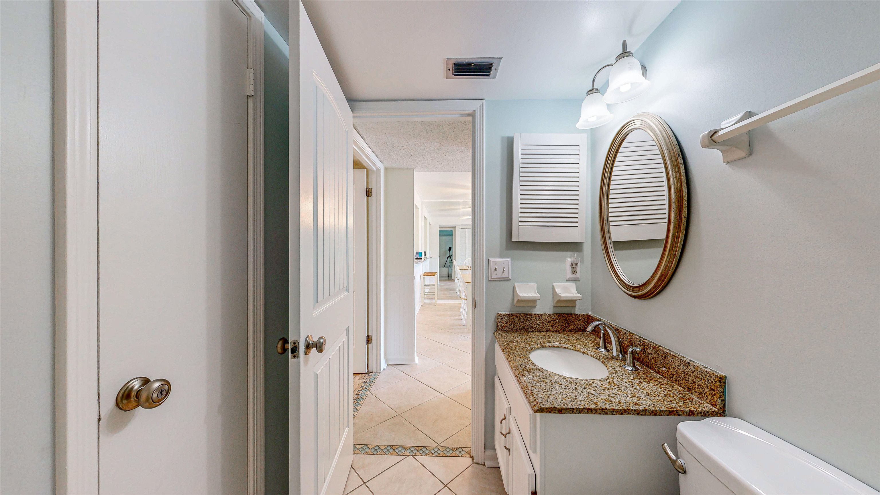 880 A1A Beach Boulevard, Unit 3207 St. Augustine, FL 32080 - Photo 16 of 33 a bathroom with a granite countertop toilet a sink and a mirror