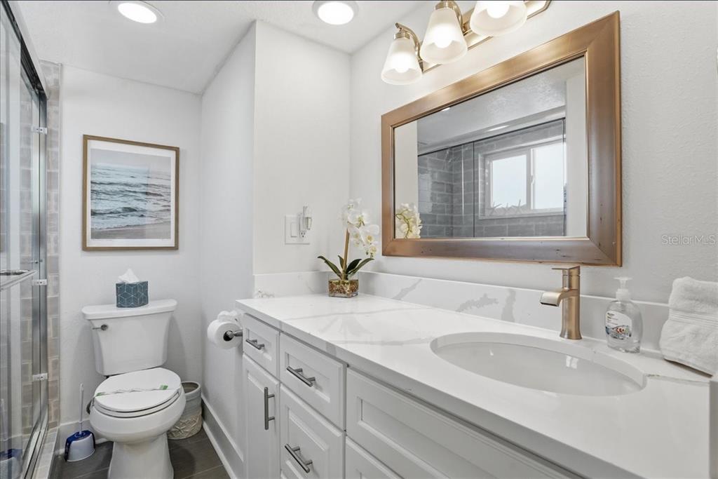 8911 Blind Pass Road, Unit 118 St. Pete Beach, FL 33706 - Photo 23 of 34 a bathroom with a toilet sink and mirror