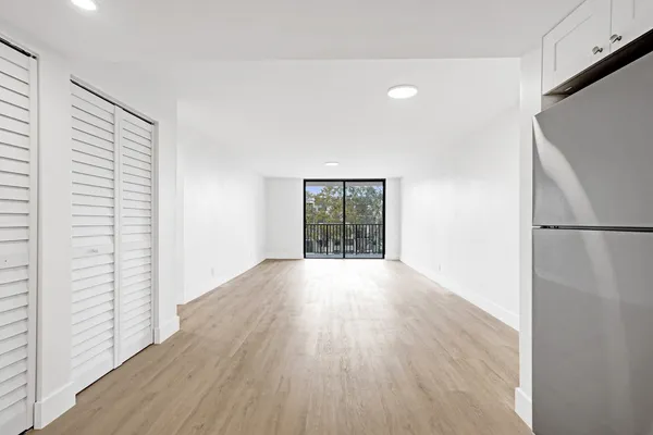 a view of an empty room with wooden floor and a window