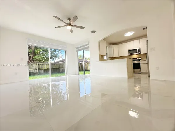a view of a kitchen with kitchen island a large window cabinets a sink and stainless steel appliances