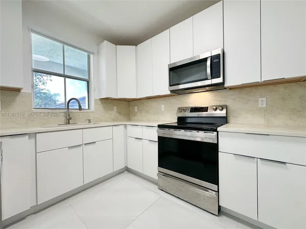 a kitchen with stainless steel appliances granite countertop white cabinets a sink and a stove