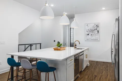 a kitchen with stainless steel appliances a dining table chairs microwave and sink