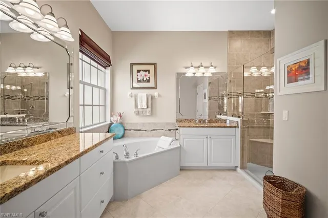 a large bathroom with a granite countertop double vanity sink a mirror and a bathtub