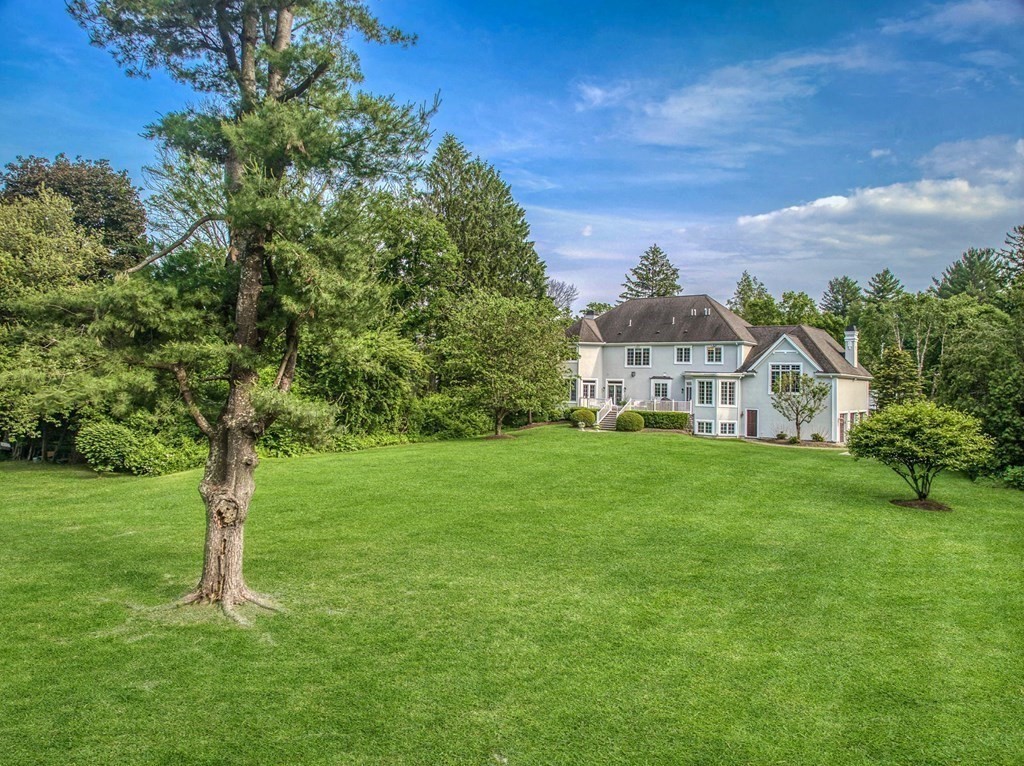 32 Bancroft Road Andover, MA 01810 - Photo 3 of 41 a view of a white house in front of a big yard with plants and large trees