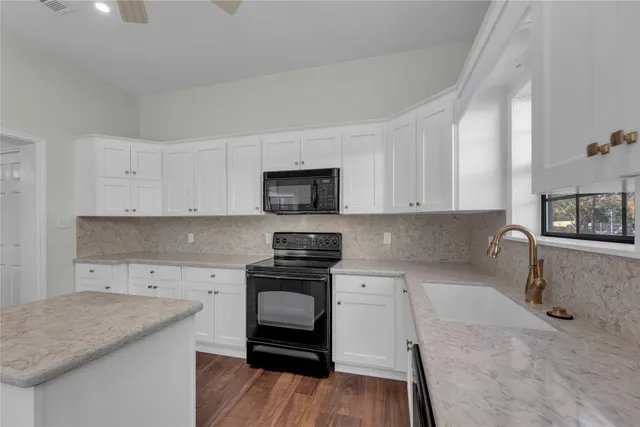 a kitchen with granite countertop a stove a sink and a microwave