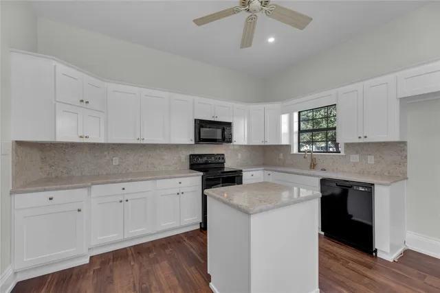 a kitchen with granite countertop stainless steel appliances a stove cabinets and wooden floor