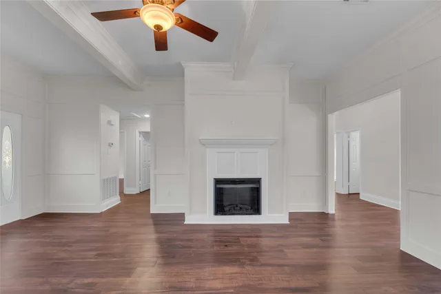 a view of an empty room with wooden floor fireplace and a window