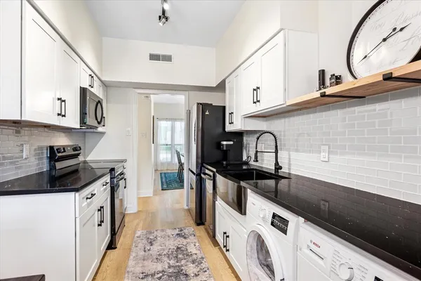 a kitchen with granite countertop a sink a stove and refrigerator