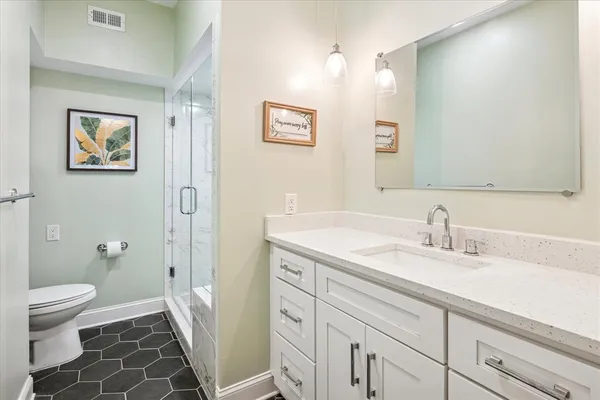 a bathroom with a granite countertop sink toilet and a mirror