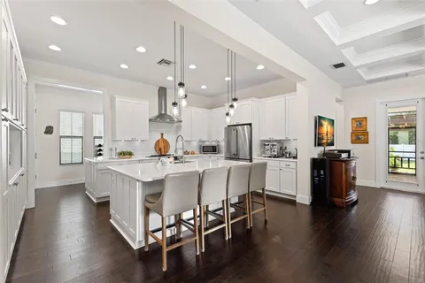 a large white dining hall with stainless steel appliances refrigerator a dining table and chairs with wooden floor