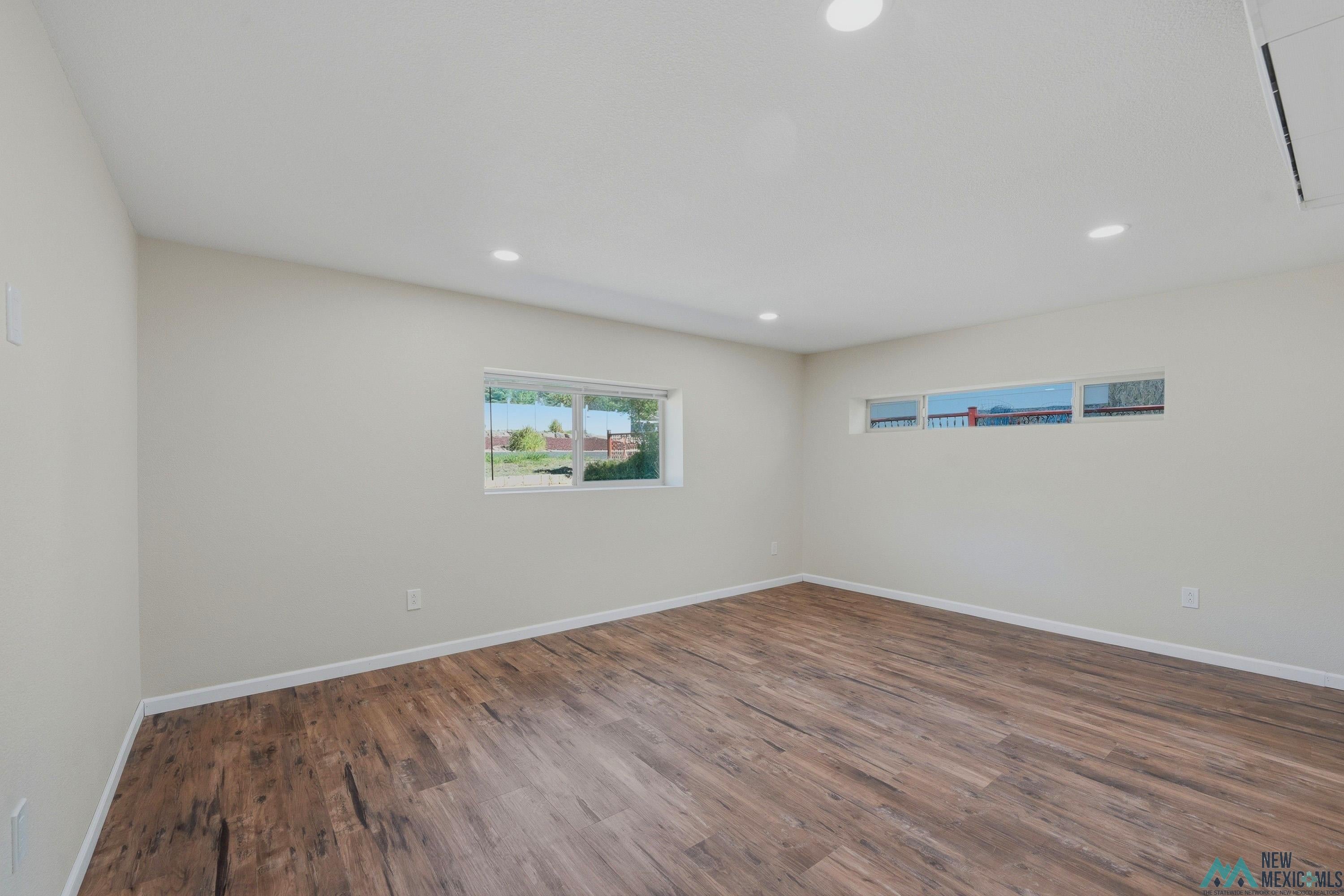 544 South 13th Avenue Raton, NM 87740 - Photo 15 of 37 Open room featuring wood-finish flooring, recessed lighting, white baseboards, and multiple windows for natural illumination