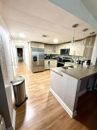 a kitchen with stainless steel appliances granite countertop a sink a stove top oven a counter space and cabinets