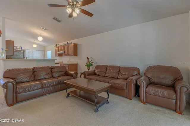 a living room with couches and a ceiling fan