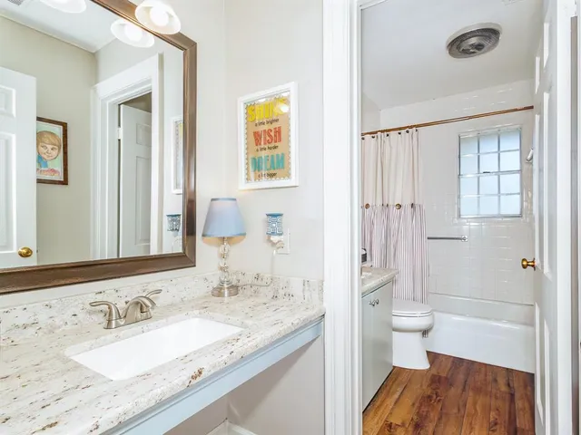 a bathroom with a granite countertop sink a toilet and shower