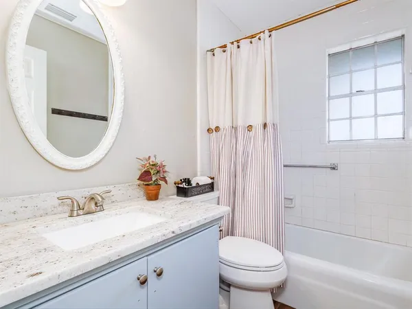 a bathroom with a granite countertop sink mirror vanity and toilet
