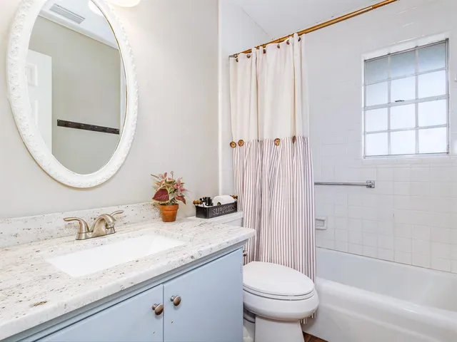 a bathroom with a granite countertop sink mirror vanity and toilet