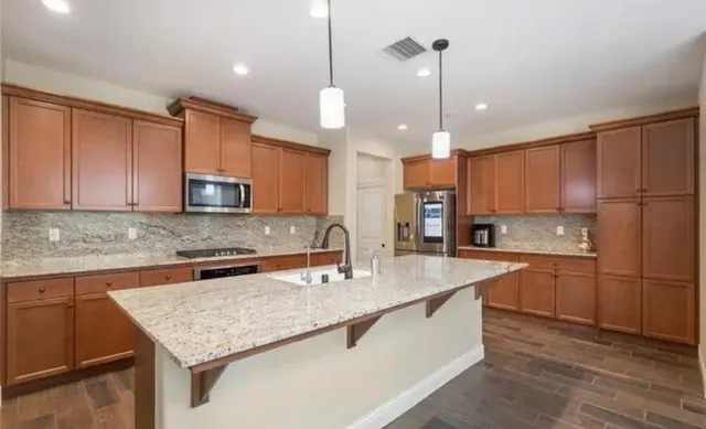 a kitchen with stainless steel appliances granite countertop a sink a stove and a wooden floor