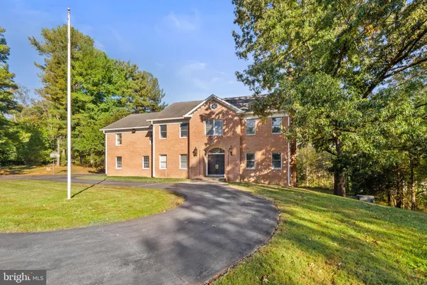 a view of a house with a big yard and large trees