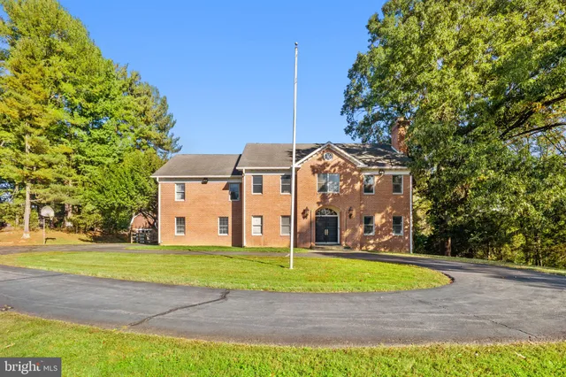 a view of a big house with a yard and large trees