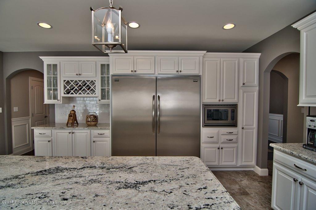 126 Highland Road Moscow, PA 18444 - Photo 34 of 77 a kitchen with stainless steel appliances kitchen island granite countertop a refrigerator a stove and a sink with wooden floor