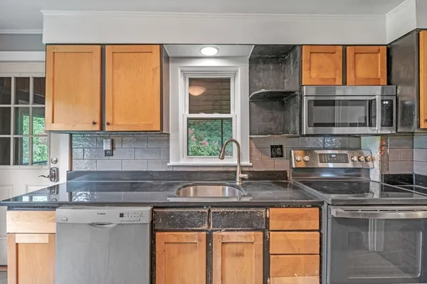 a kitchen with stainless steel appliances granite countertop a sink a stove and a microwave