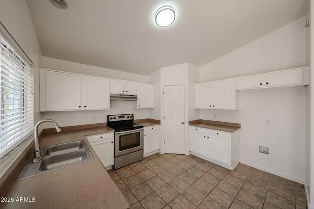 a kitchen with granite countertop a stove sink and cabinets