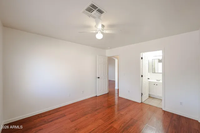 an empty room with wooden floor and ceiling fan