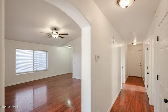 a view of an empty room with chandelier fan and wooden floor