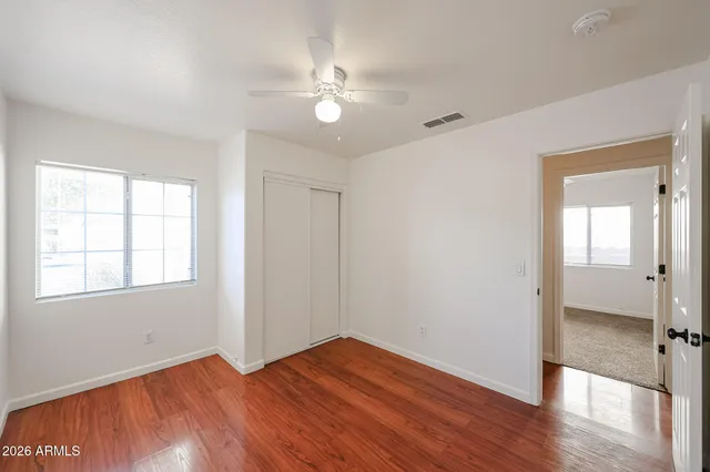 an empty room with wooden floor and windows