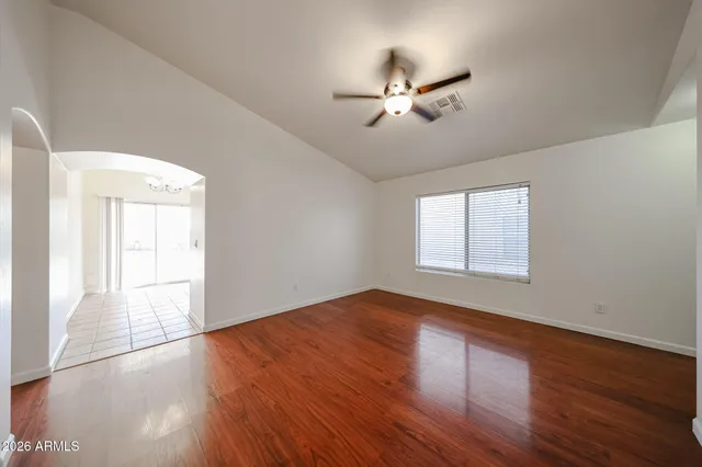 a view of empty room with wooden floor and fan