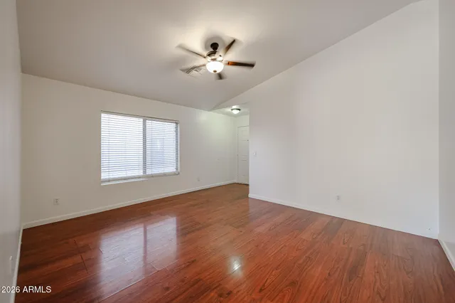a view of an empty room with wooden floor and a window