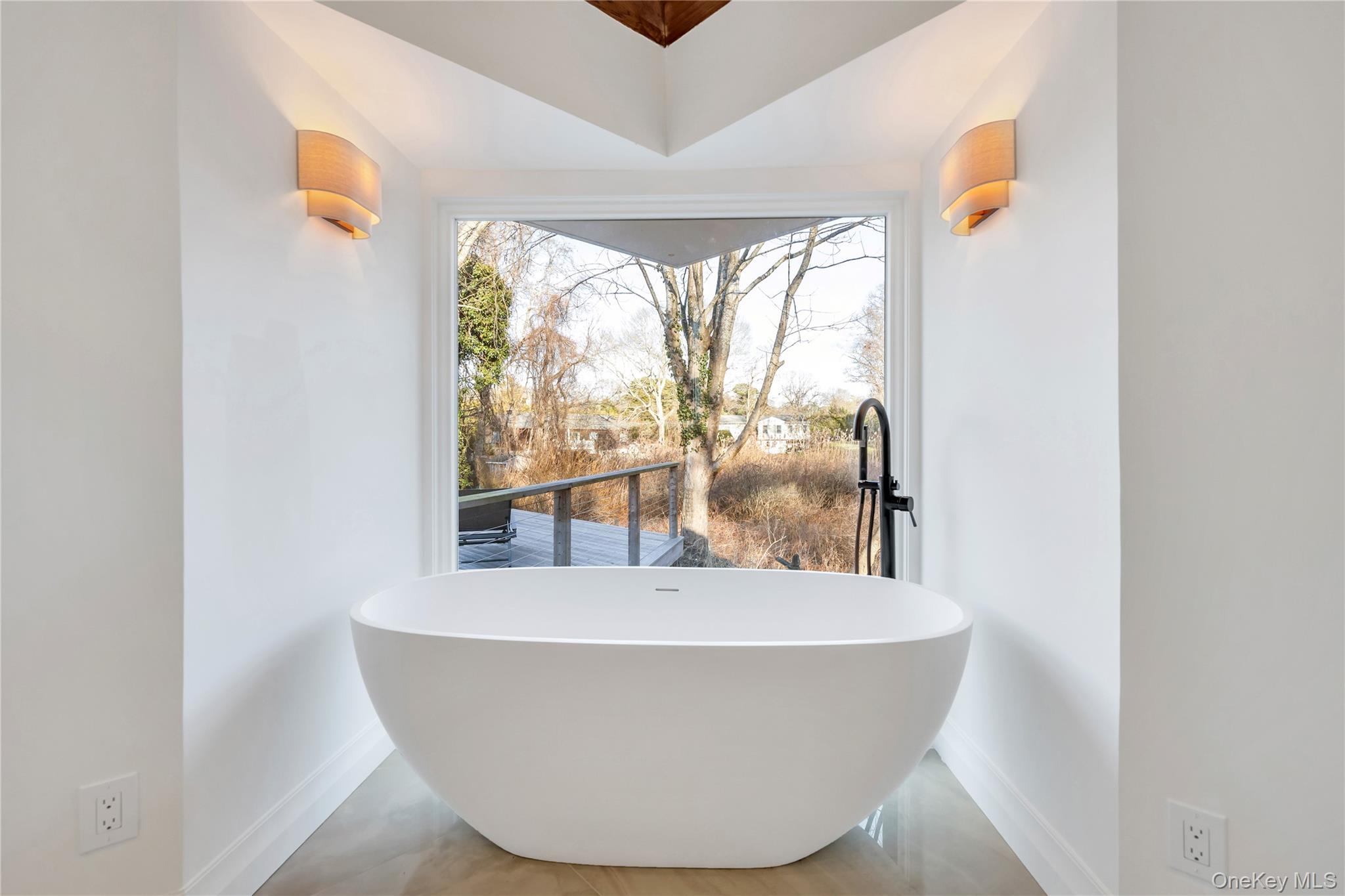 10 Lenape Road Southampton, NY 11968 - Photo 24 of 37 a white bath tub sitting in a bathroom next to a window
