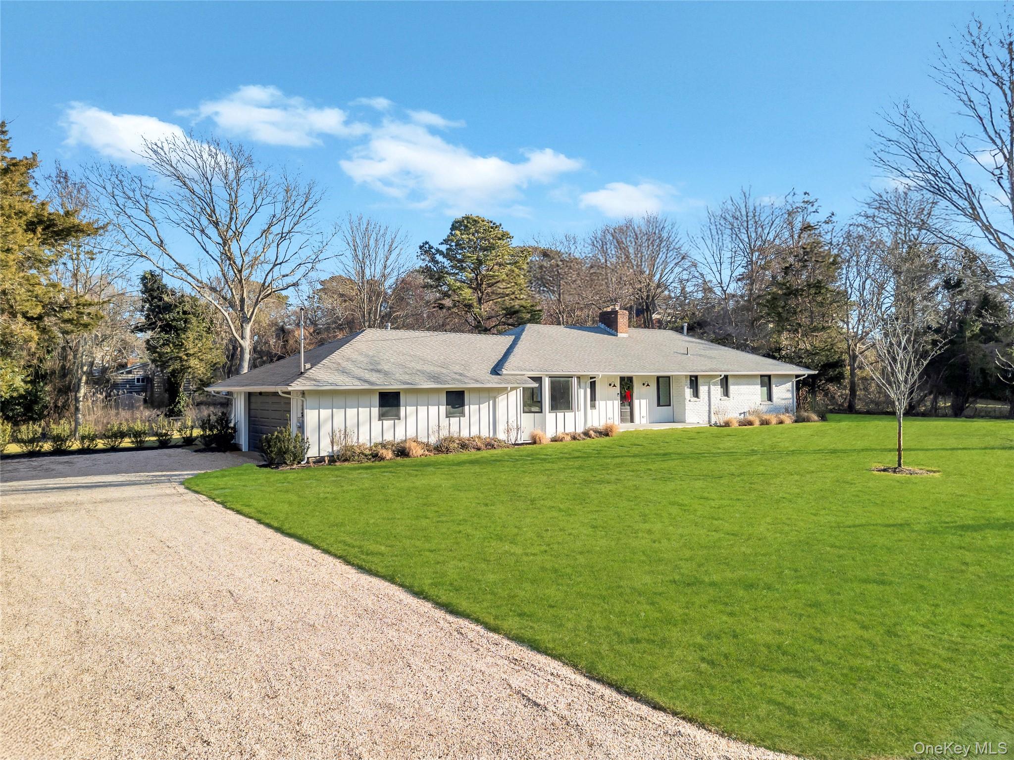 10 Lenape Road Southampton, NY 11968 - Photo 4 of 16 Ranch-style house with board and batten siding, gravel driveway, a front yard, and a chimney