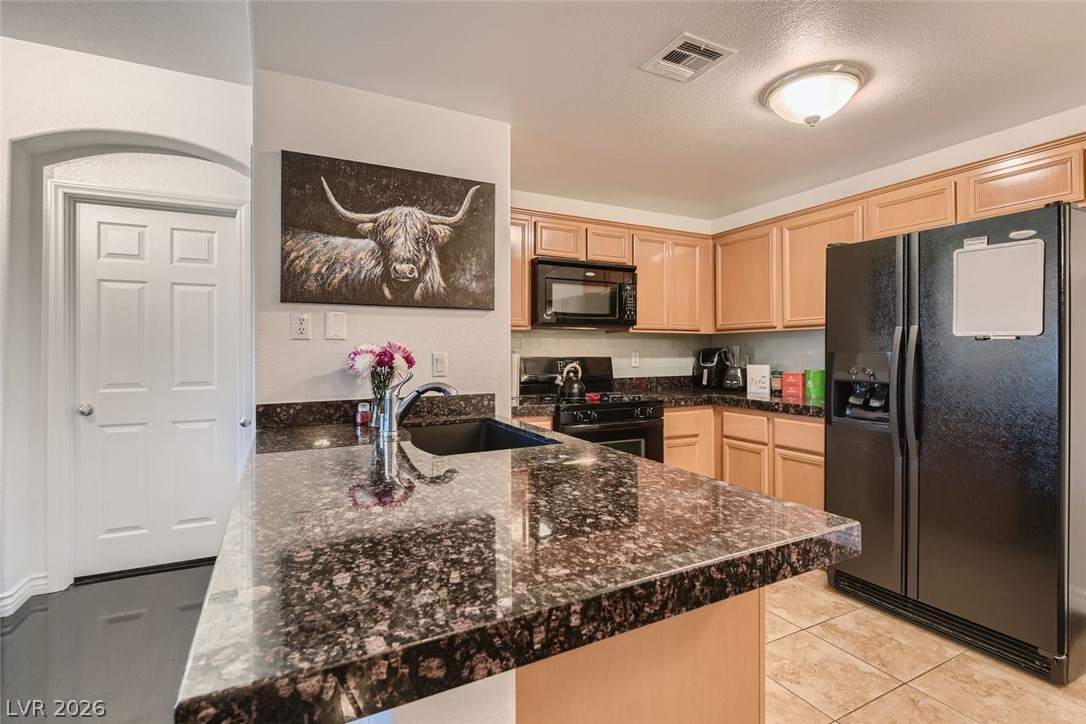 7701 West Robindale Road, Unit 265 Las Vegas, NV 89113 - Photo 12 of 27 Polished granite countertops complement natural wood cabinetry in this well-appointed kitchen.
