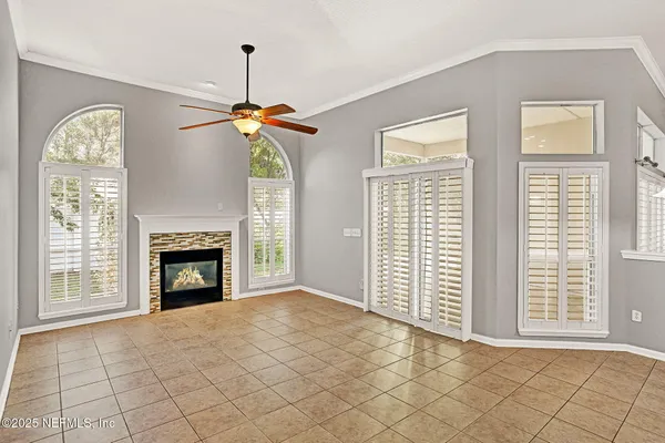 a view of an empty room with window and chandelier fan
