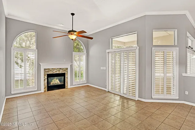 a view of an empty room with window and chandelier fan