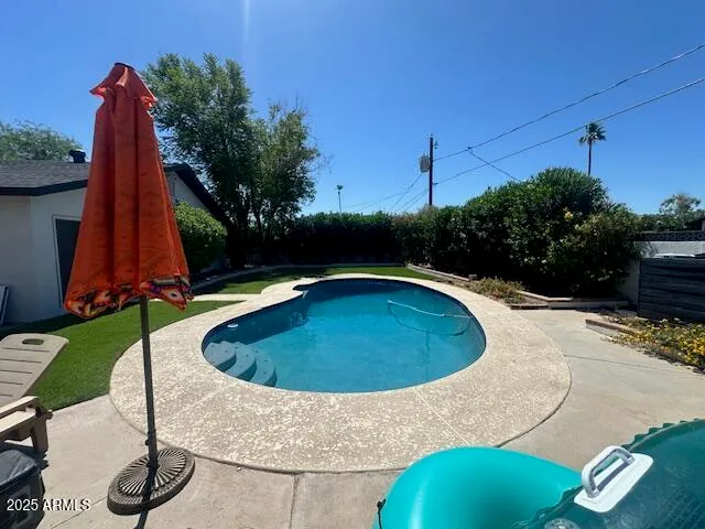 a view of a swimming pool with a yard and sitting area
